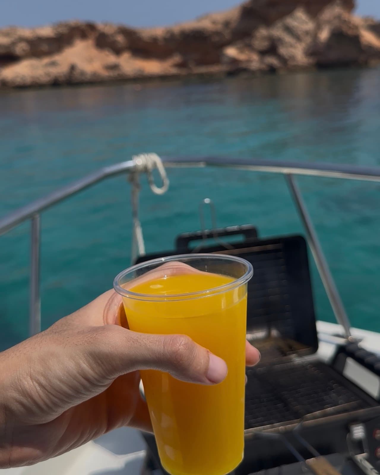 Fresh orange juice held up on the bow of a Horizon Blue boat off the Daymaniyat Islands