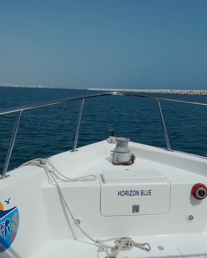 Bow of a Horizon Blue boat heading out across open sea from Muscat