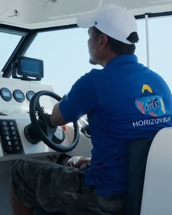 Horizon Blue captain at the helm on the crossing to the Daymaniyat Islands